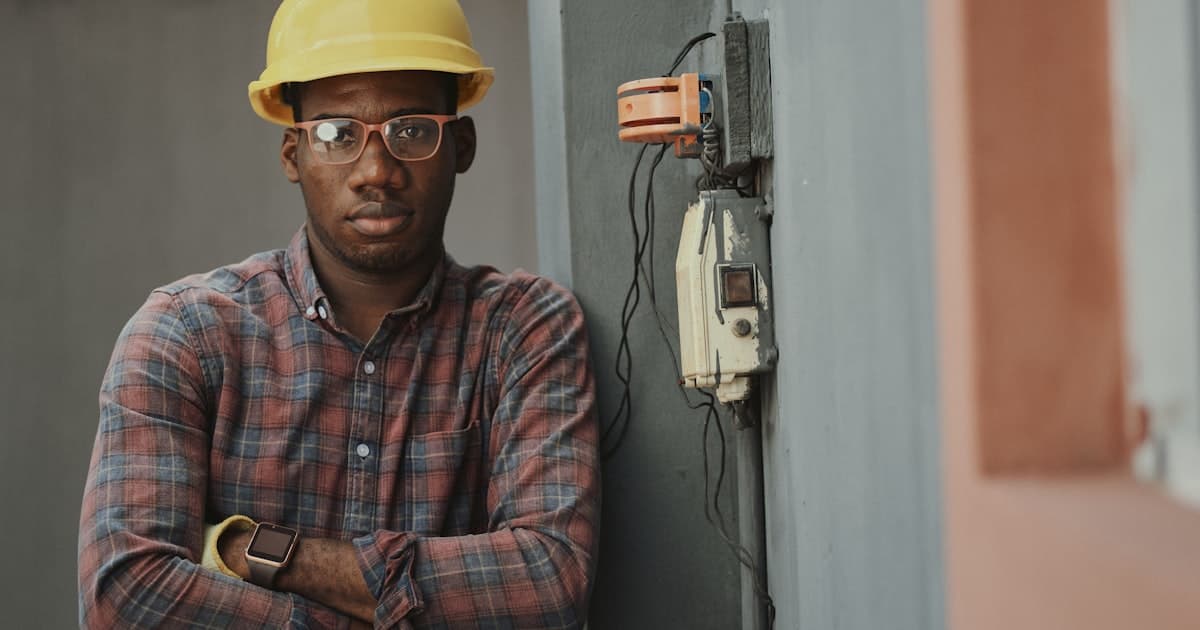 Contractor in hard hat standing next to electrical panel on job site